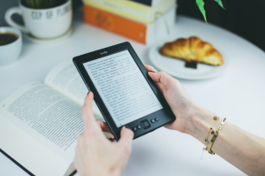 holding a kindle and a book on the background